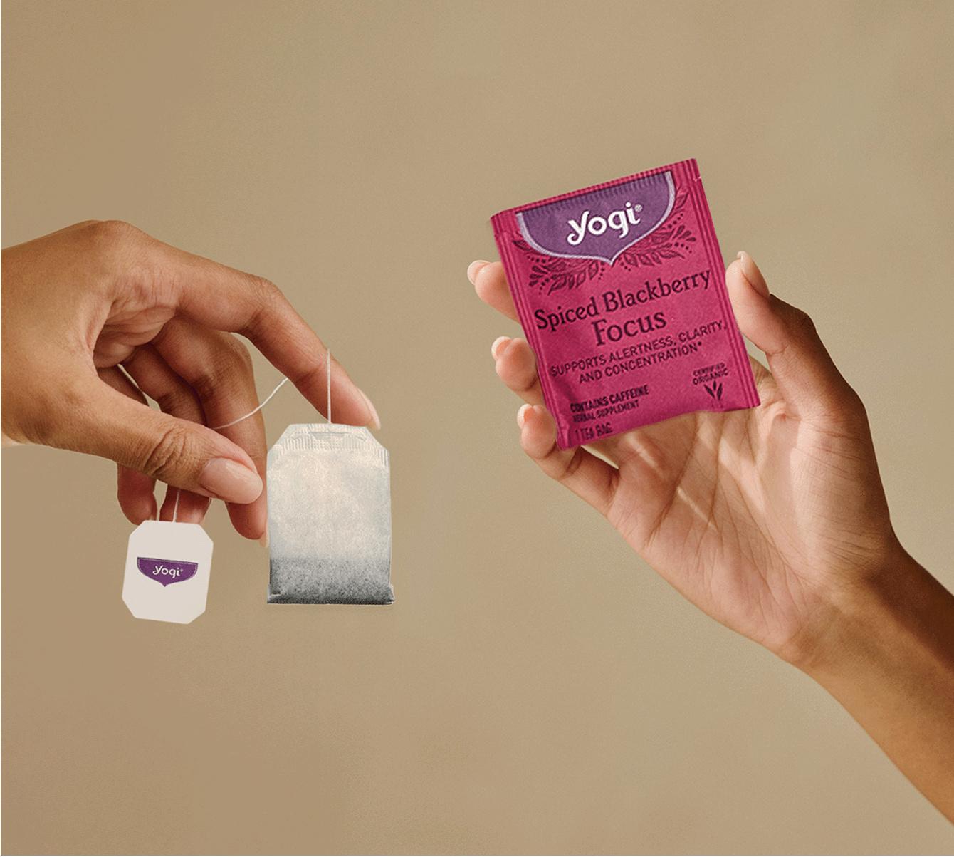 Hands holding a spiced blackberry tea bag and package