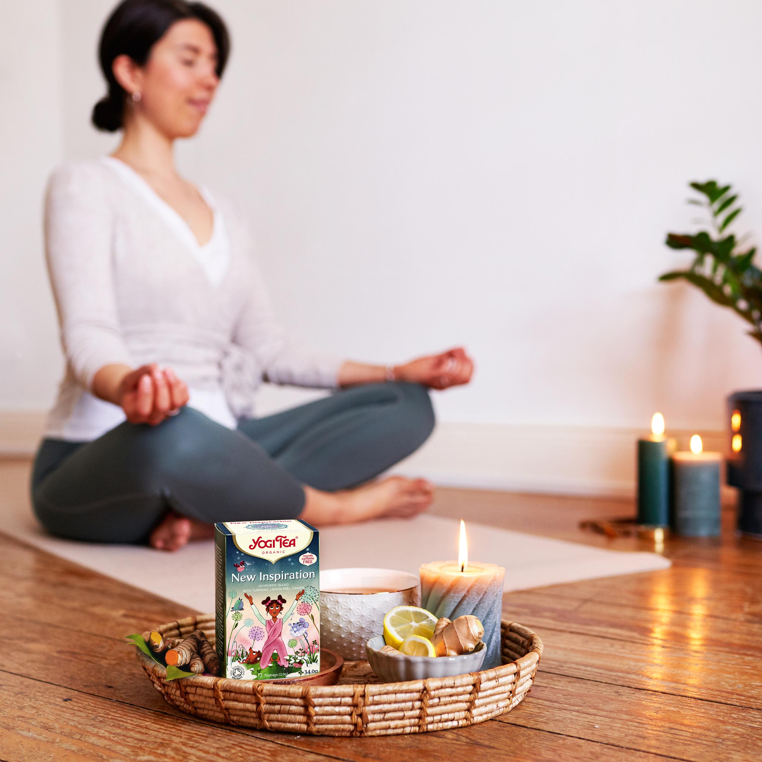 Yogi Tea New Inspiration organic herbal tea during yoga meditation ritual with candle, teacup and wellness setting