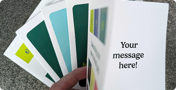 Fanned stack of folded cards showing various designs with one opened to the text shown inside "Your message here!"