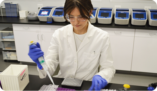 A woman wearing goggles using lab equipment