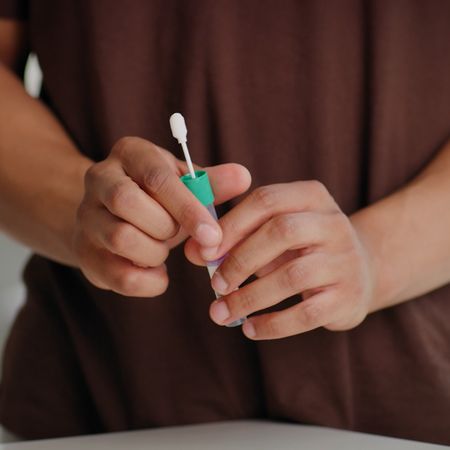Closeup of a man holding the sample tube with swab attachment.