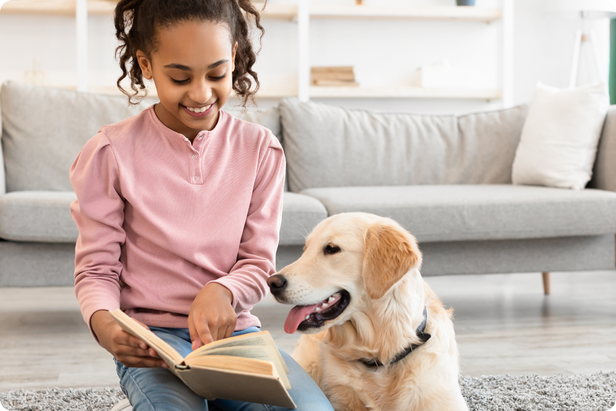 Young girl reads book with dog at home