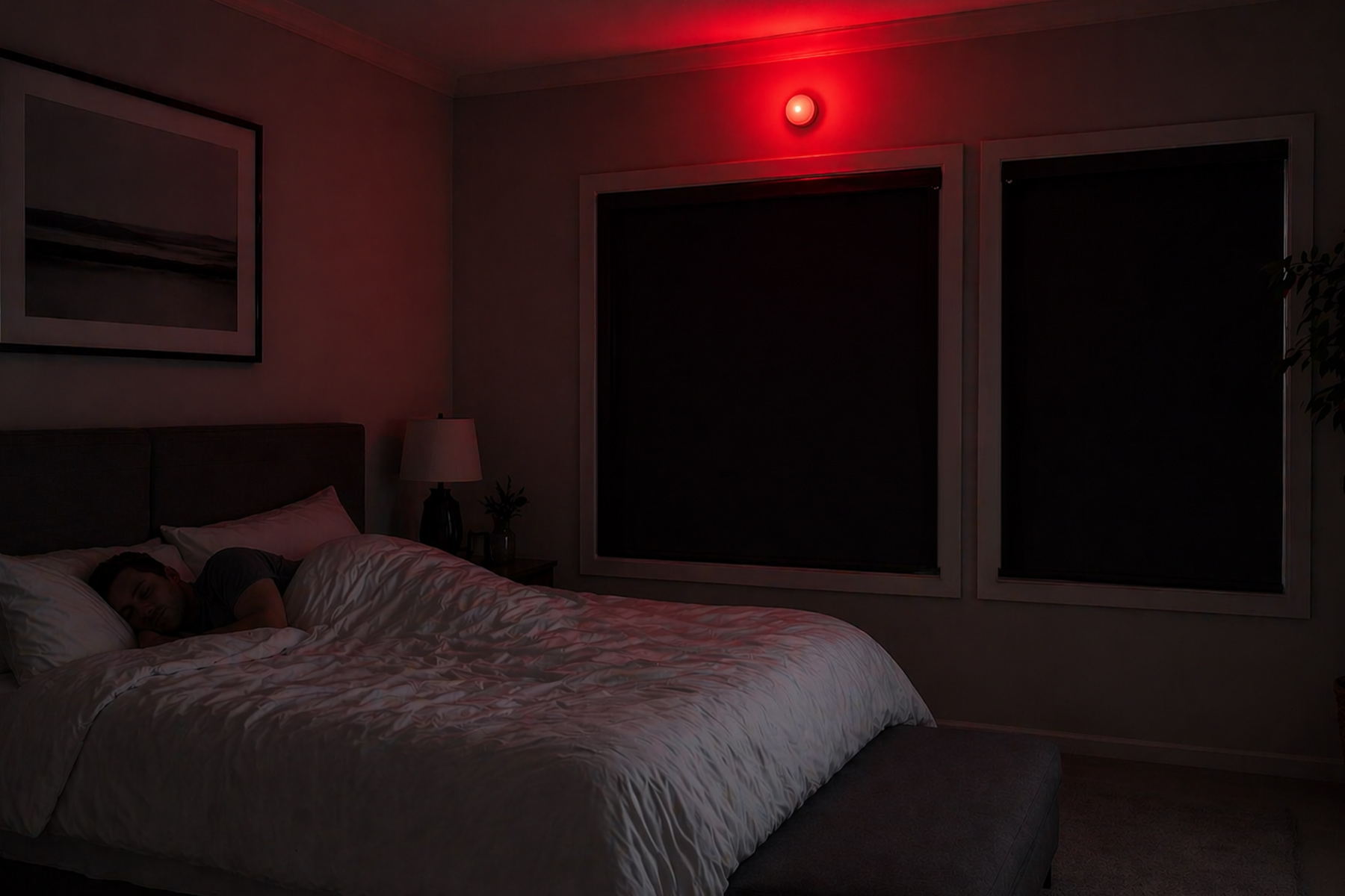 Sleeping person in pitch-black bedroom with red motion sensor light softly illuminating bed