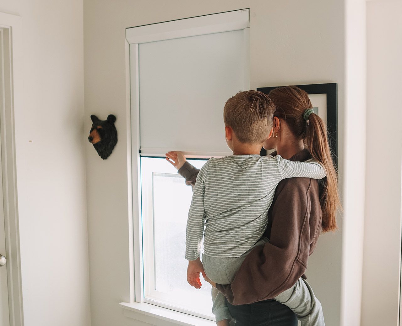 Mother holding toddler pointing at UBlockout cordless top down bottom up shade lowered from top for privacy in child's room