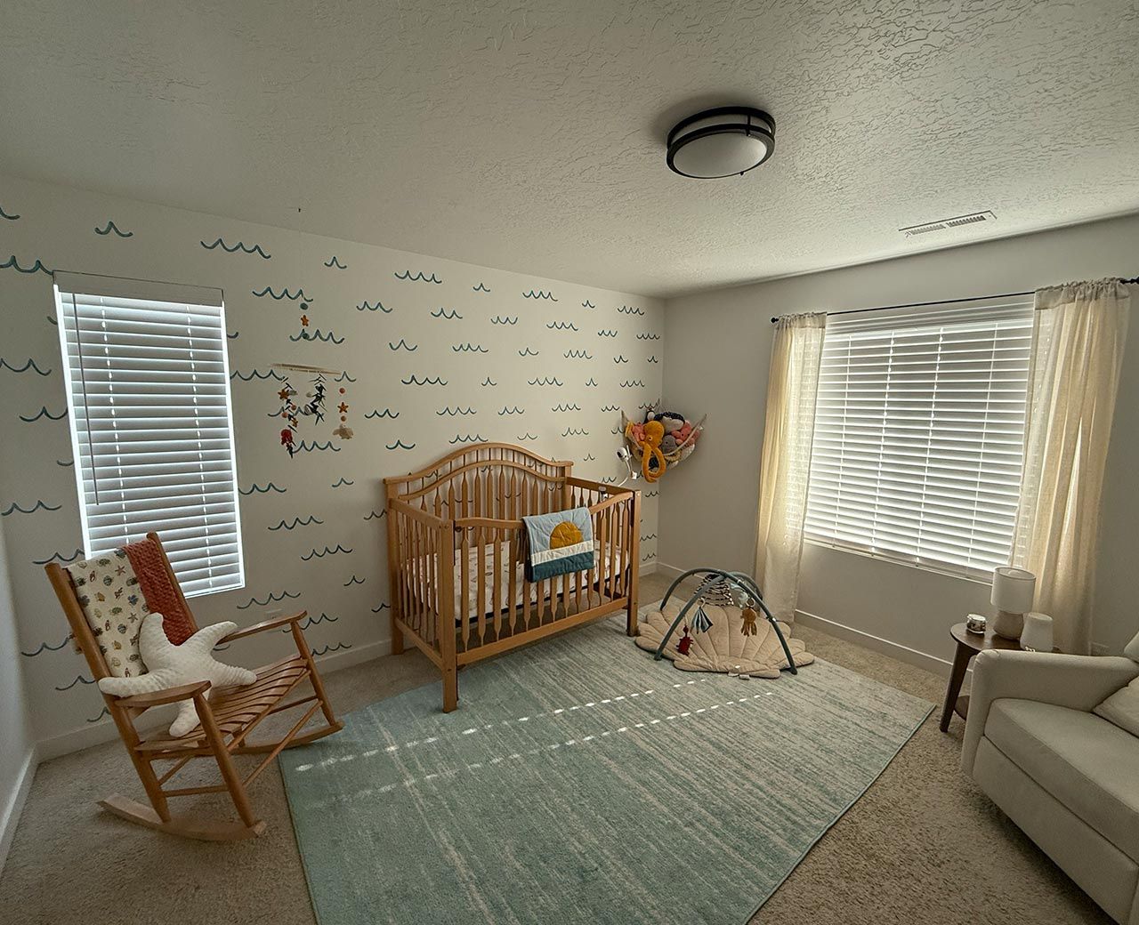 Ocean-themed nursery with standard blinds showing visible light gaps around edges that disrupt infant sleep