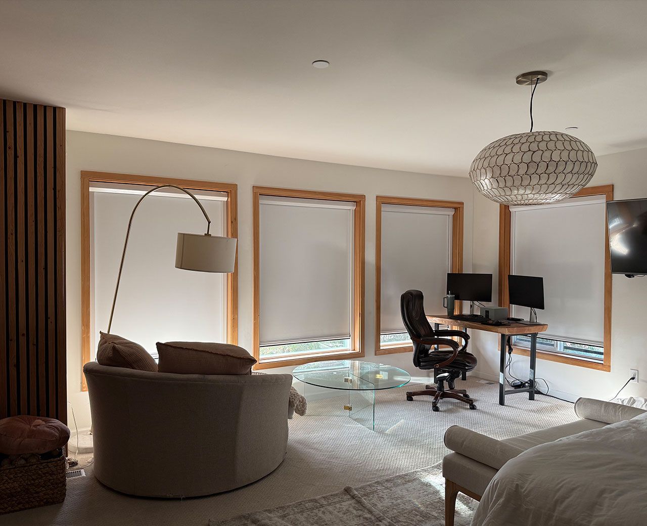  Living room with multiple room darkening roller shades showing light glowing through white fabric across four windows during the day