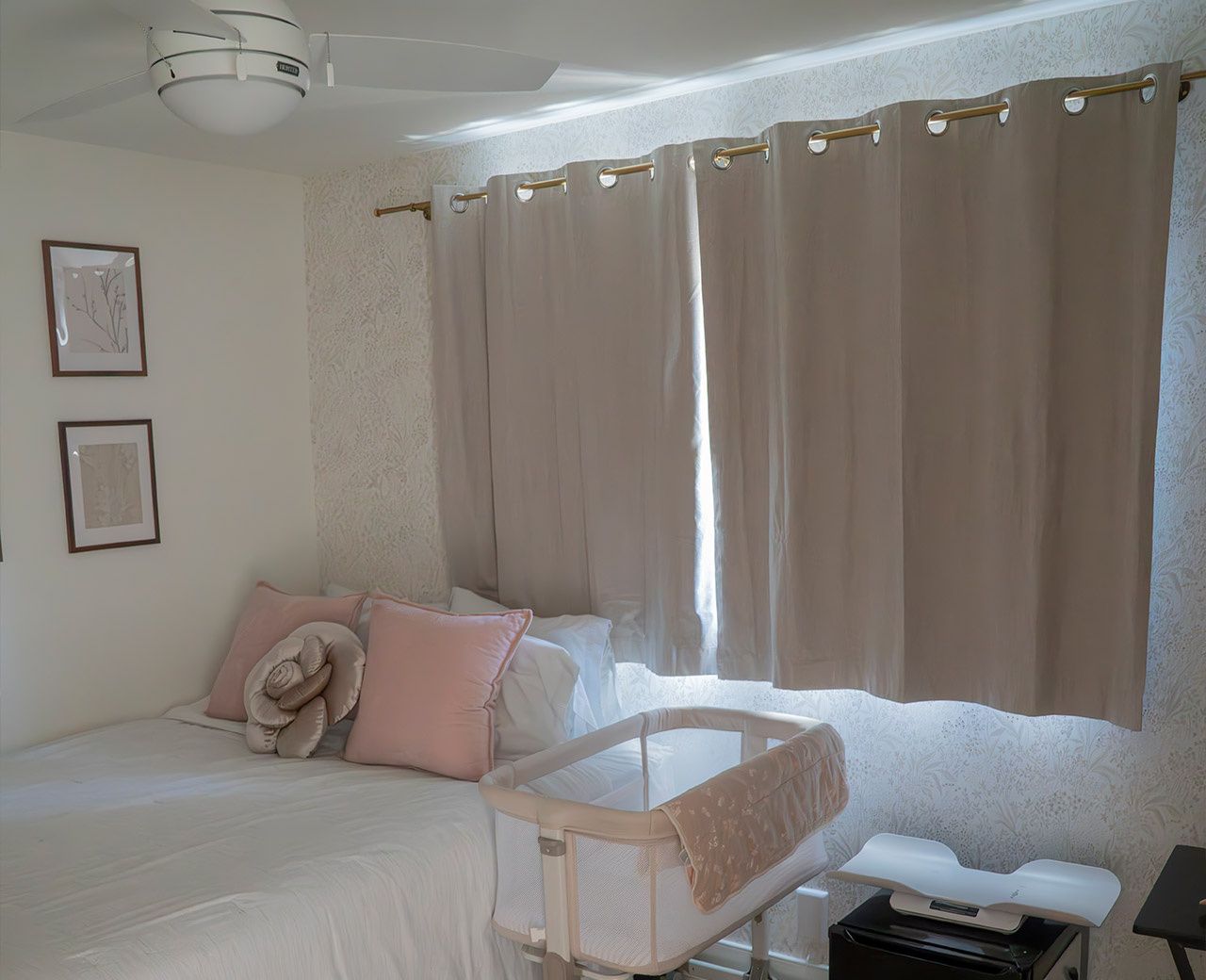 Bedroom with beige grommet curtains showing significant light gaps at the top and sides, with bed featuring pink and white bedding and a white bassinet visible