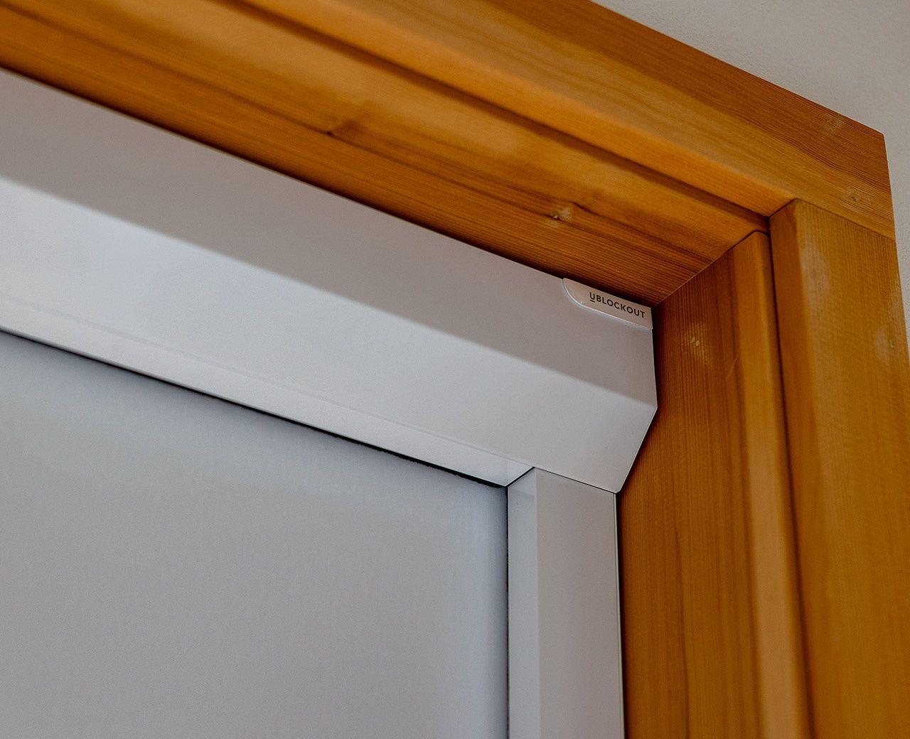 Close-up of UBlockout sealed track system corner installation on wooden window frame showing precision engineering