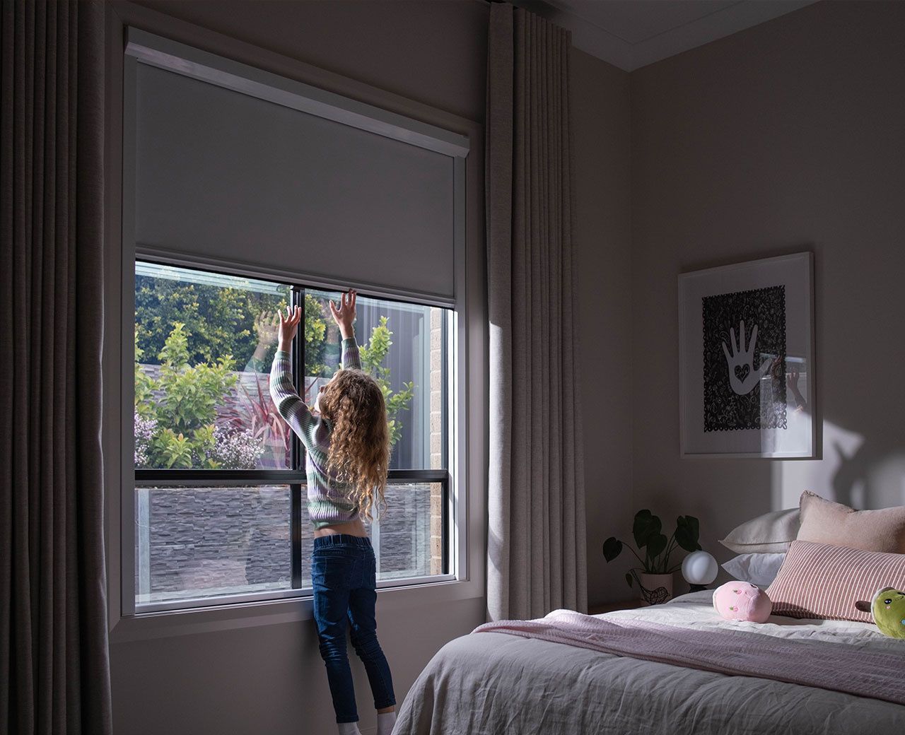 Child easily operating UBlockout blackout shade in bedroom with natural outdoor view
