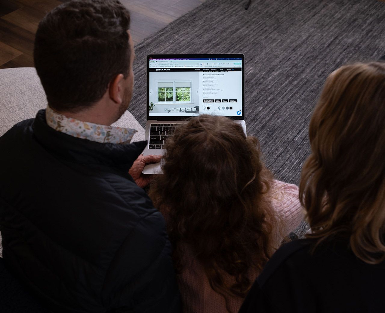 Family browsing the UBlockout website on a laptop to choose a blackout shade for their home