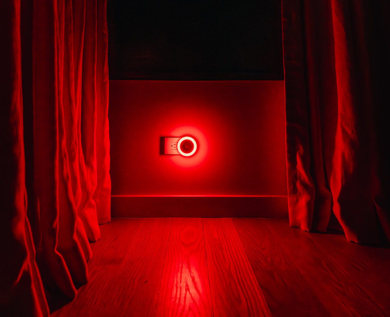 uBlockout motion-activated red night light glowing between blackout curtains in a dark room