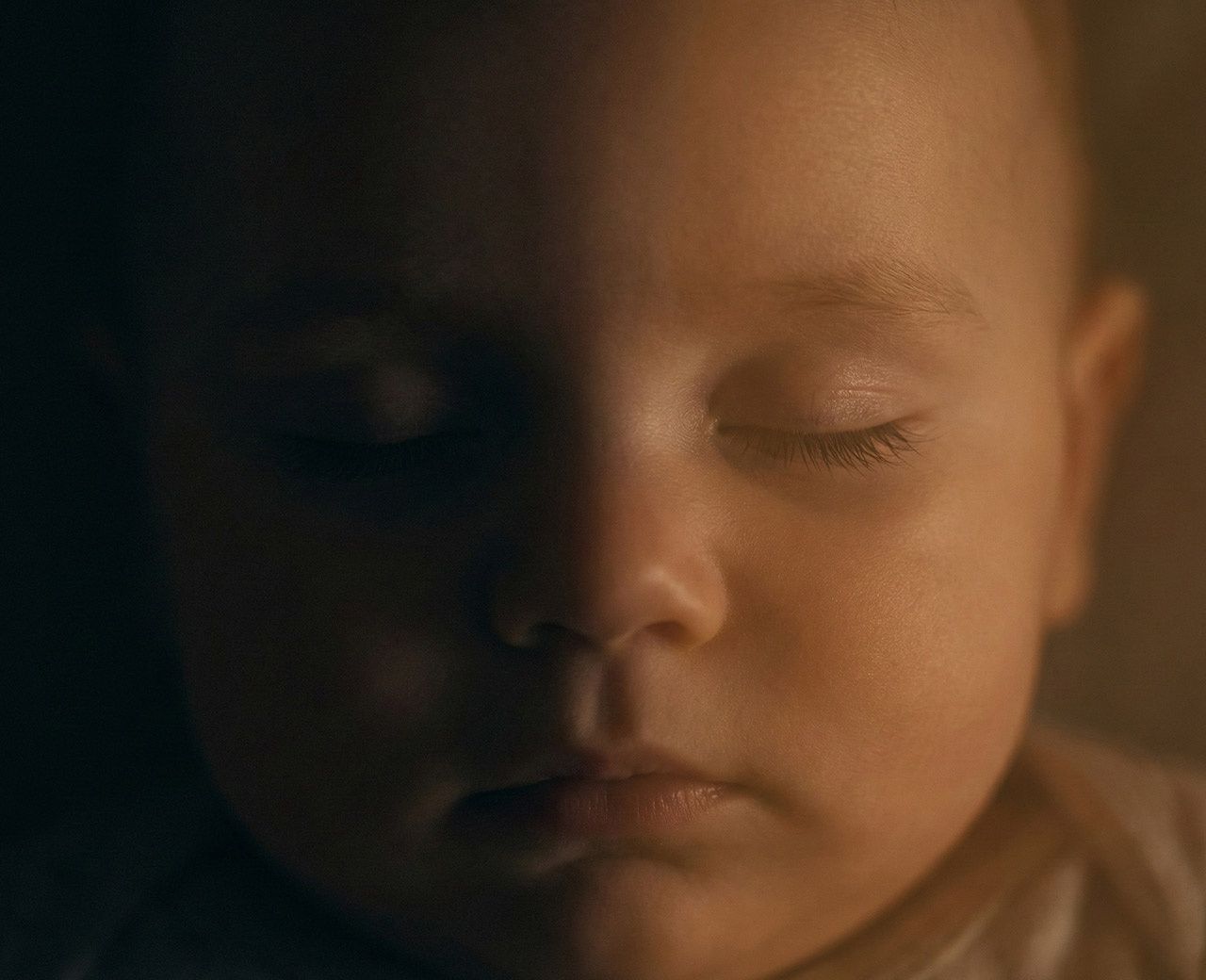 Close-up of sleeping baby’s face softly lit by warm night light