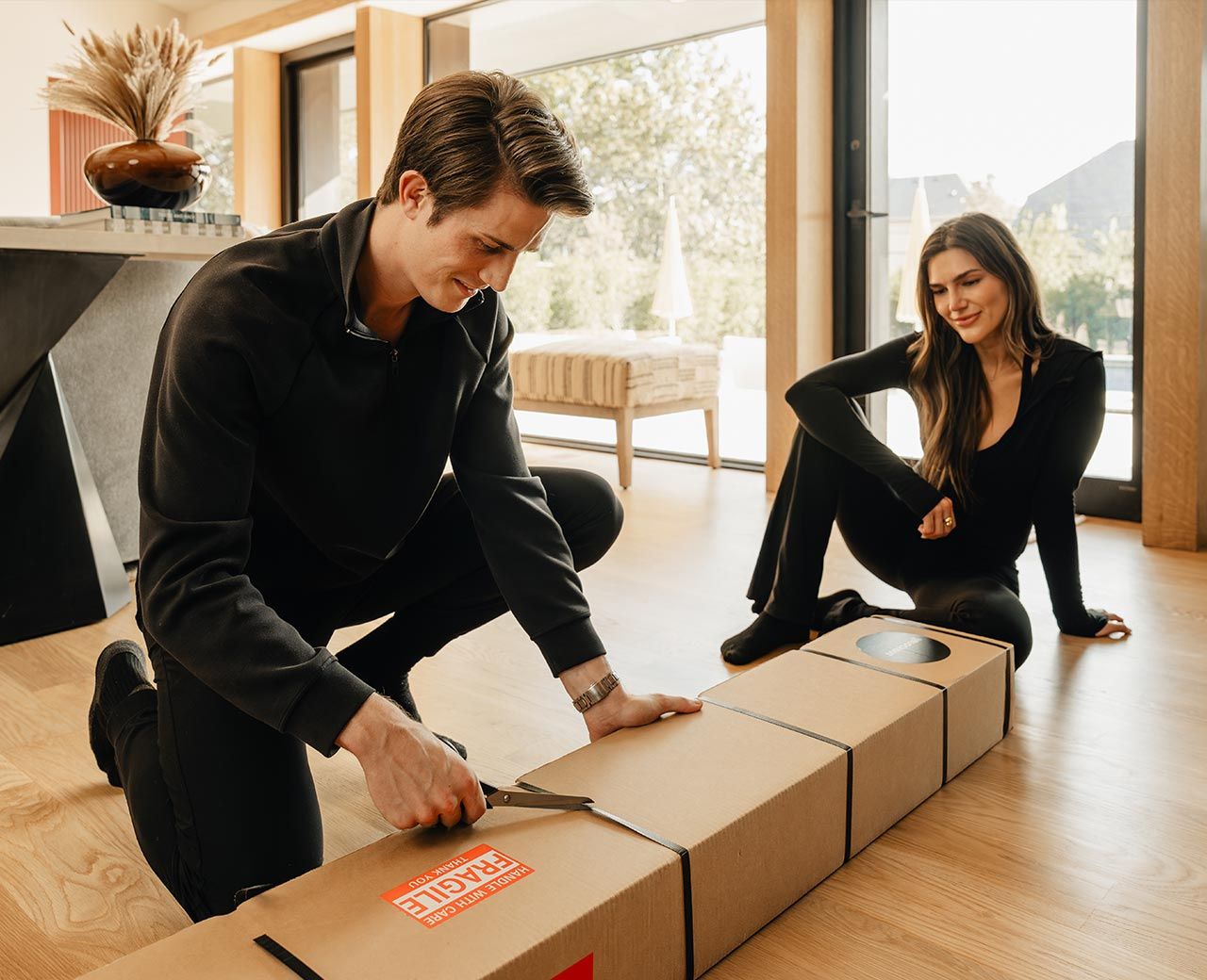 Couple opening uBlockout shades box on floor in bright modern living space