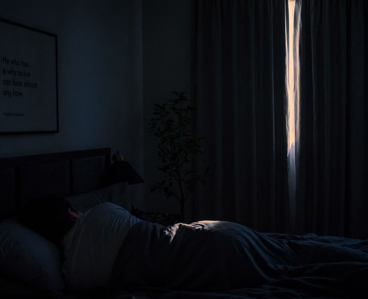 Early morning light leaking through curtain into dark bedroom, casting strip of light across sleeping person