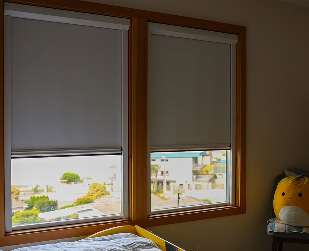 Dual windows with uBlockout shades partially lowered reducing daylight in bedroom