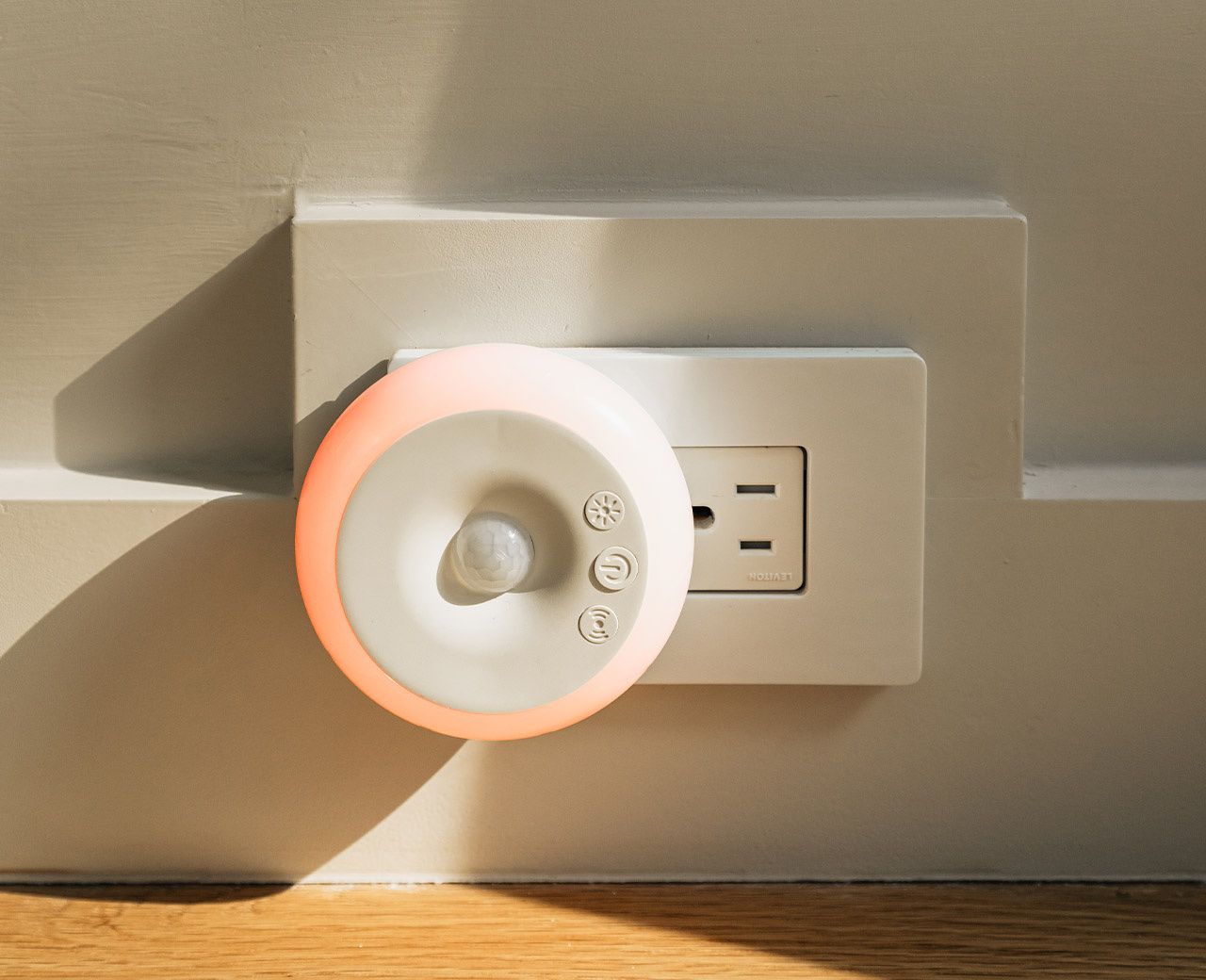 Close-up of uBlockout red light motion sensor night light plugged into wall outlet