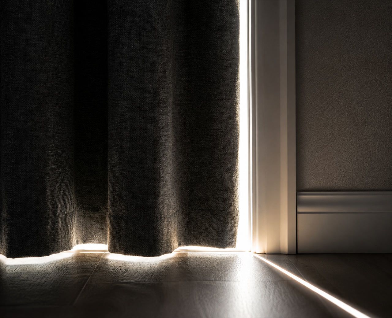 Bright morning sunlight leaking around the edges and bottom gap of a bedroom curtain.