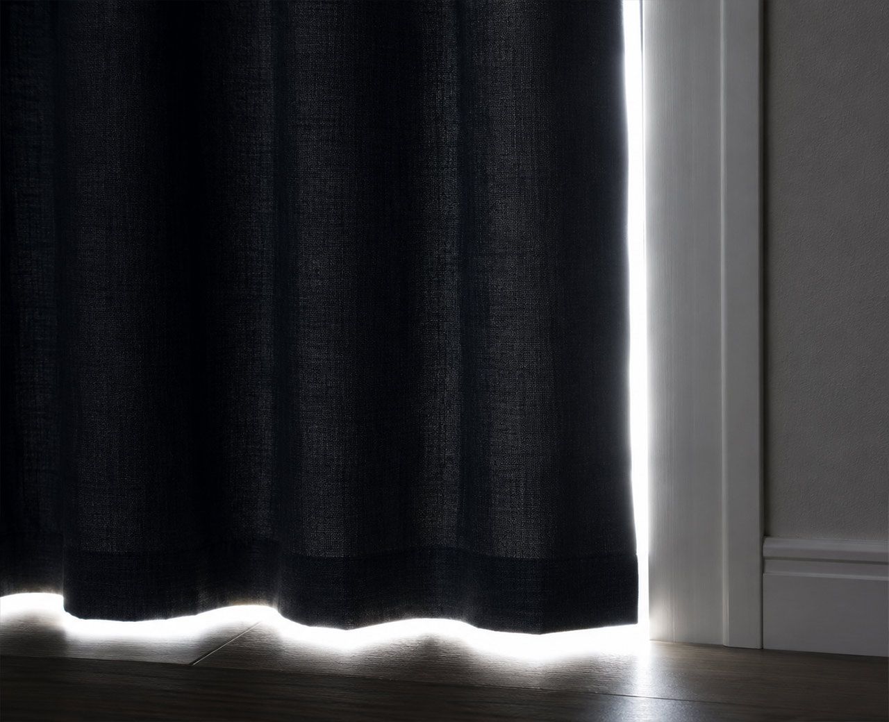 Bright daylight leaking through the side and bottom gaps of a dark bedroom curtain.