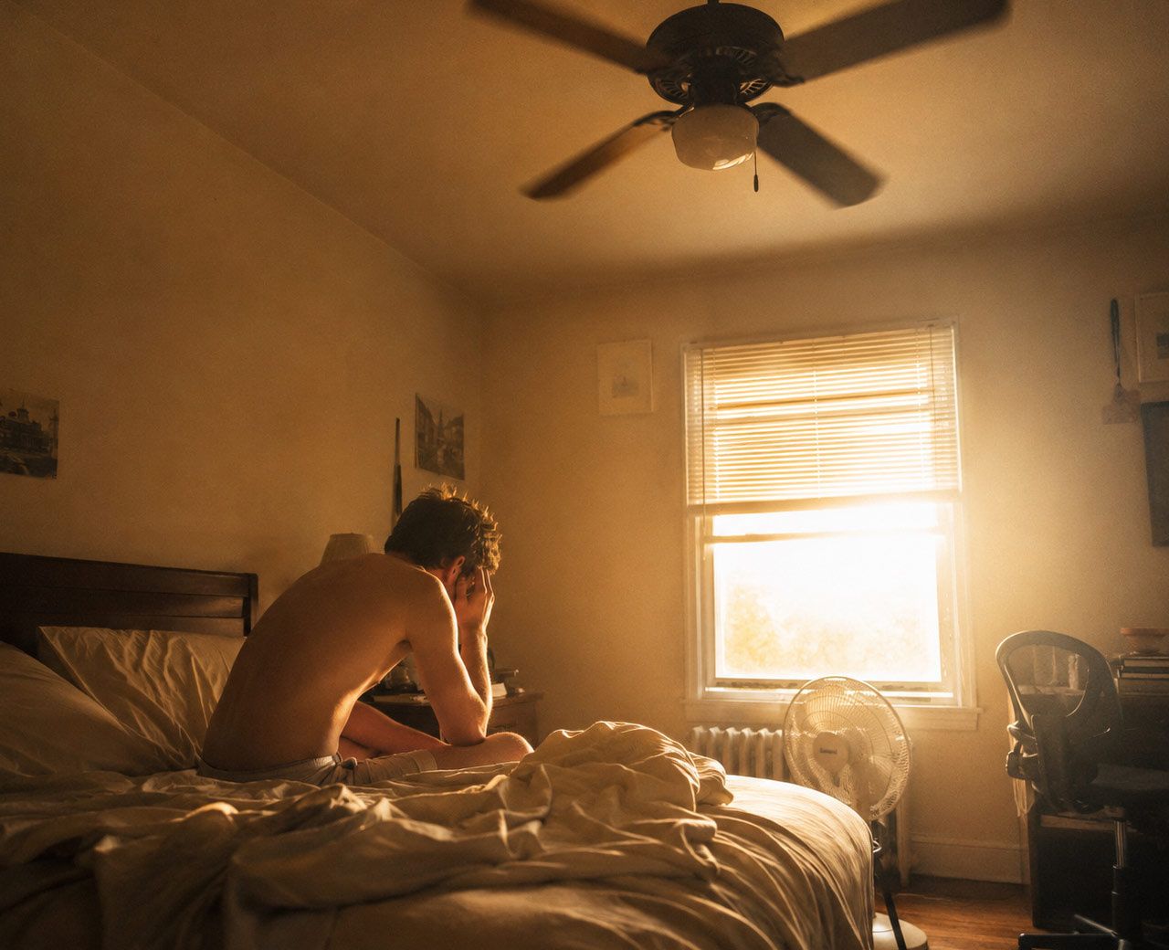 Stuffy upper floor bedroom on a hot day with harsh window light and a ceiling fan overhead