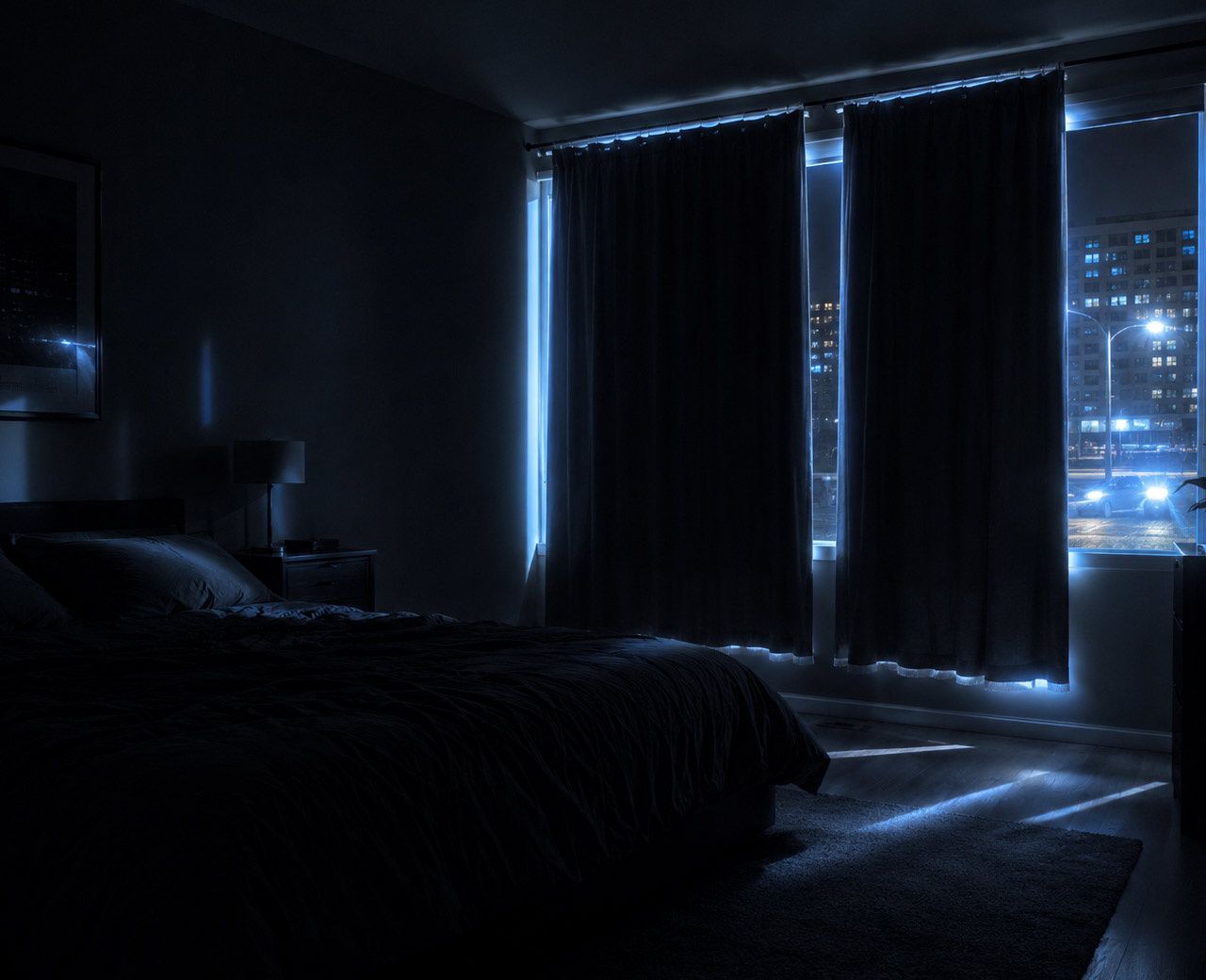 Dark bedroom at night with urban streetlight and ambient city glow flooding in through gaps in window curtains
