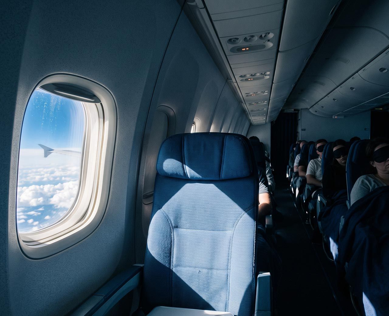 Dark aircraft cabin with bright daylight coming through an open window shade during a long flight