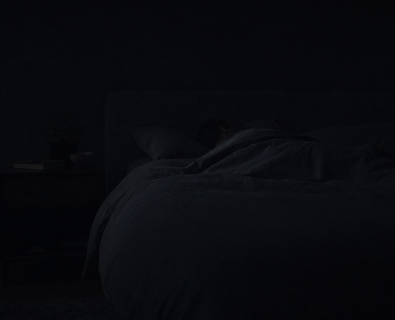 Almost completely dark bedroom with the faint outline of a person sleeping