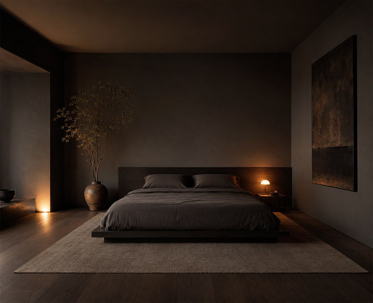 Wide view of a calm dark bedroom with charcoal walls, low bed and warm low lighting