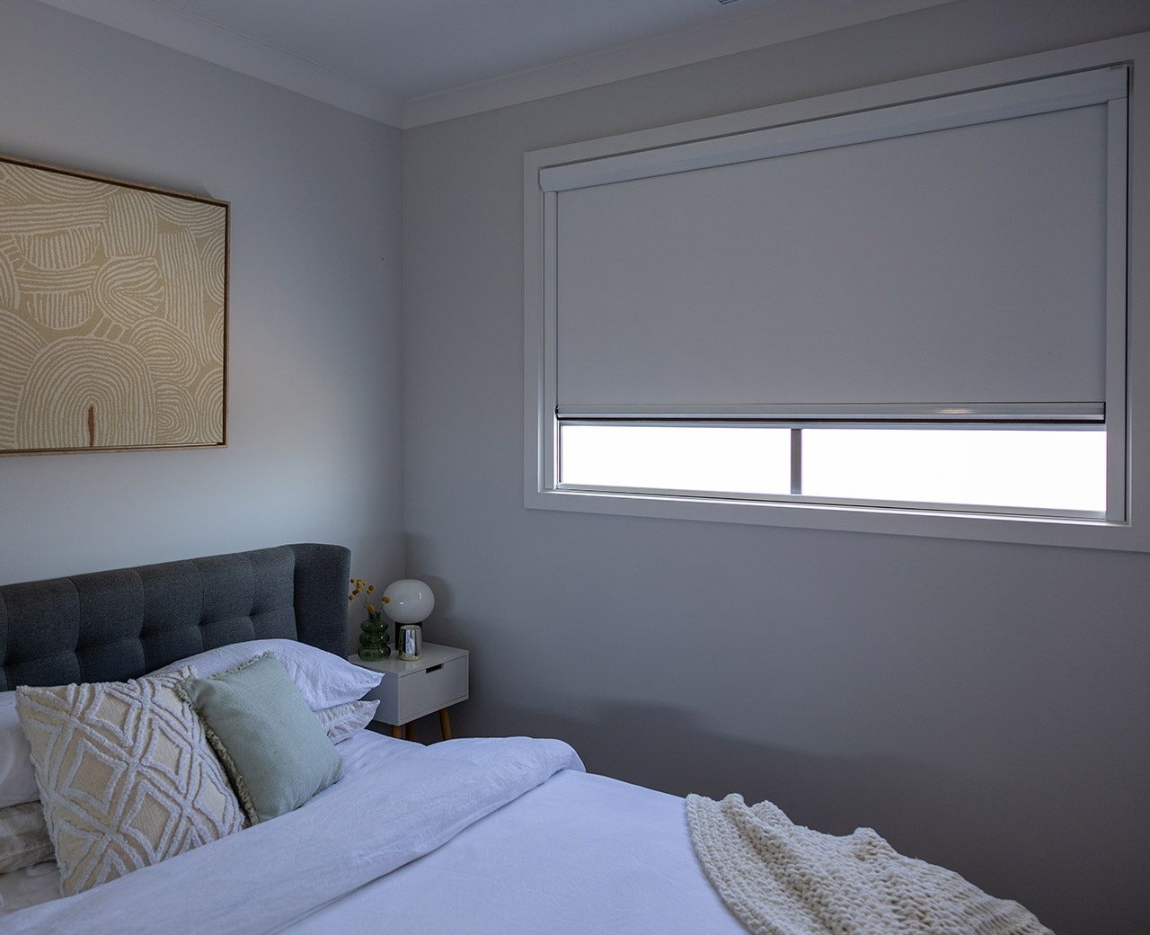 uBlockout blackout roller shade partially lowered on bedroom window reducing daylight