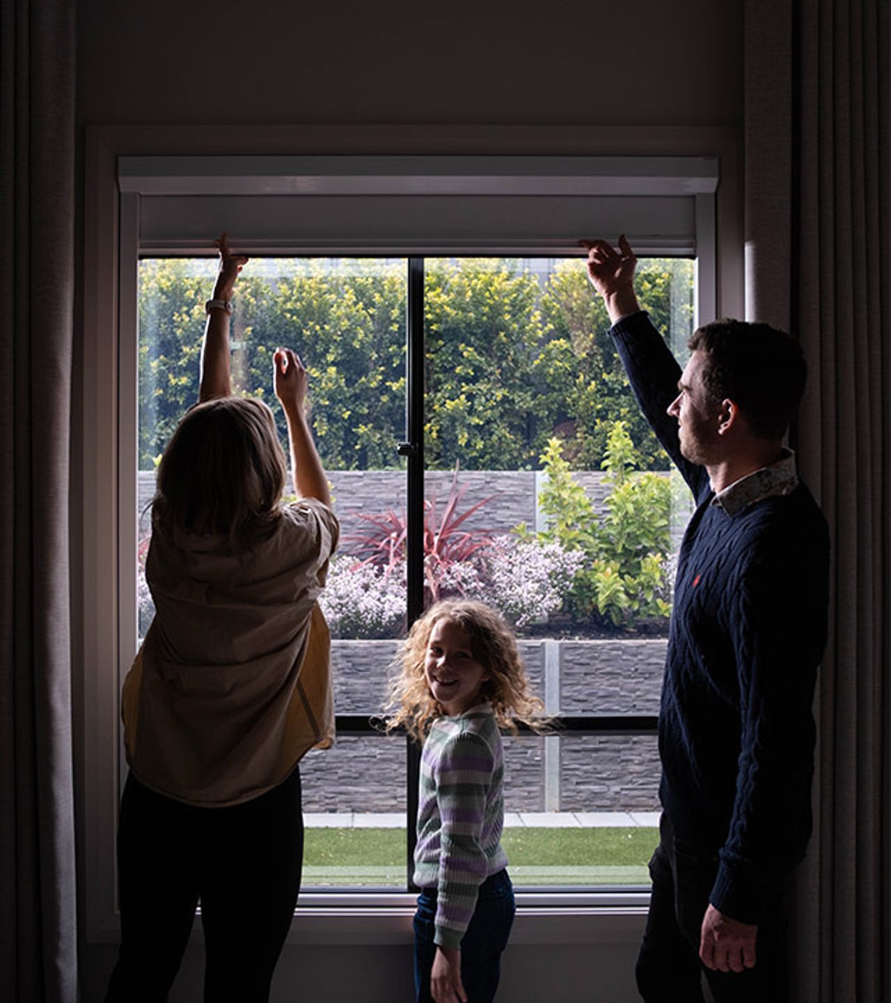Happy family pulling down a UBlockout shade in their daughters bedroom 
