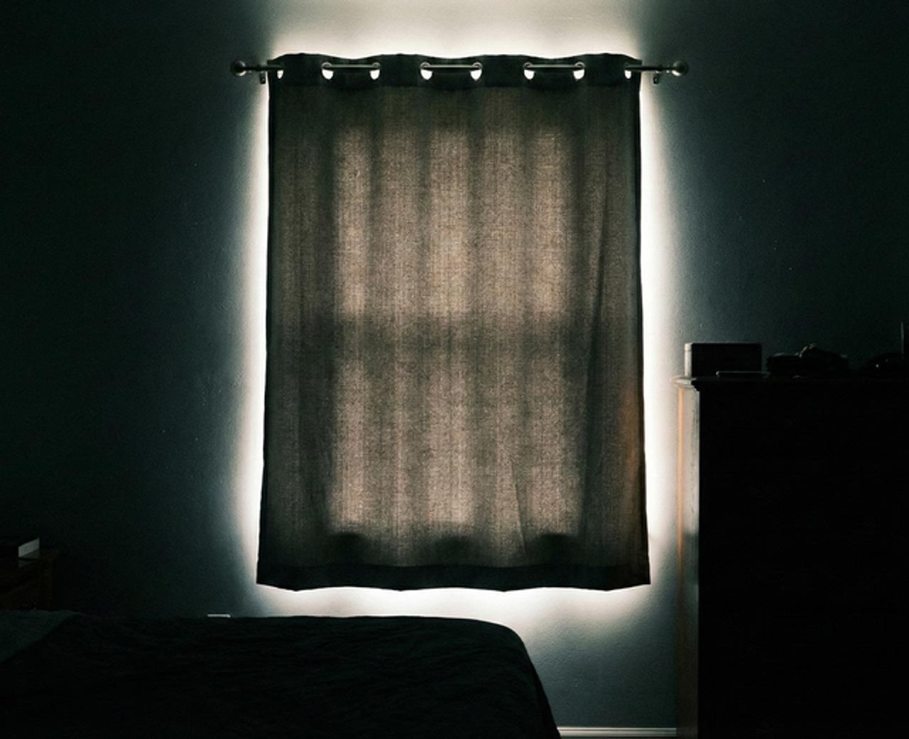 Blackout curtain on rod with bright light halo visible around all four edges in dark bedroom