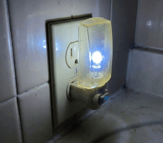Standard plug-in night light emitting harsh blue-white LED light in bathroom