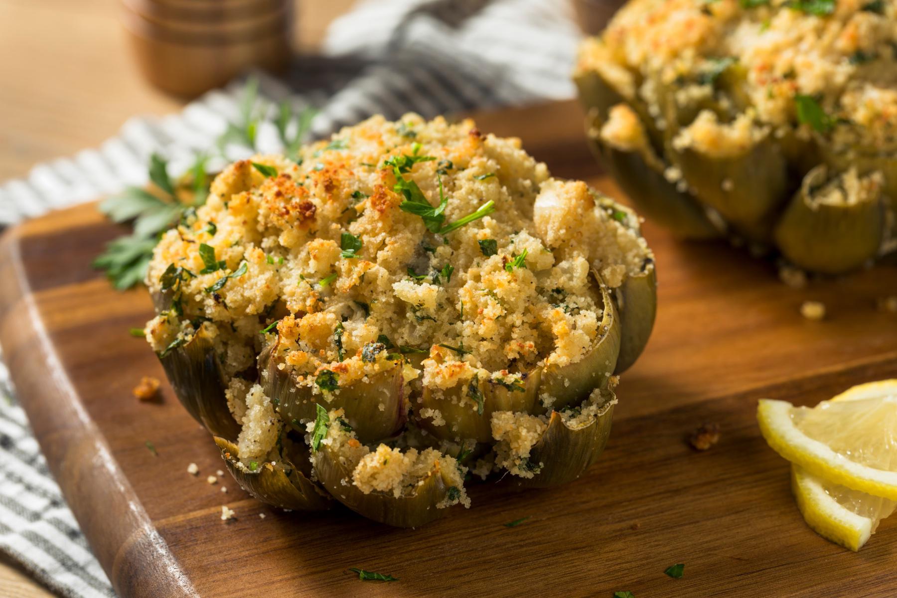 A stuffed artichoke on a wooden plate.