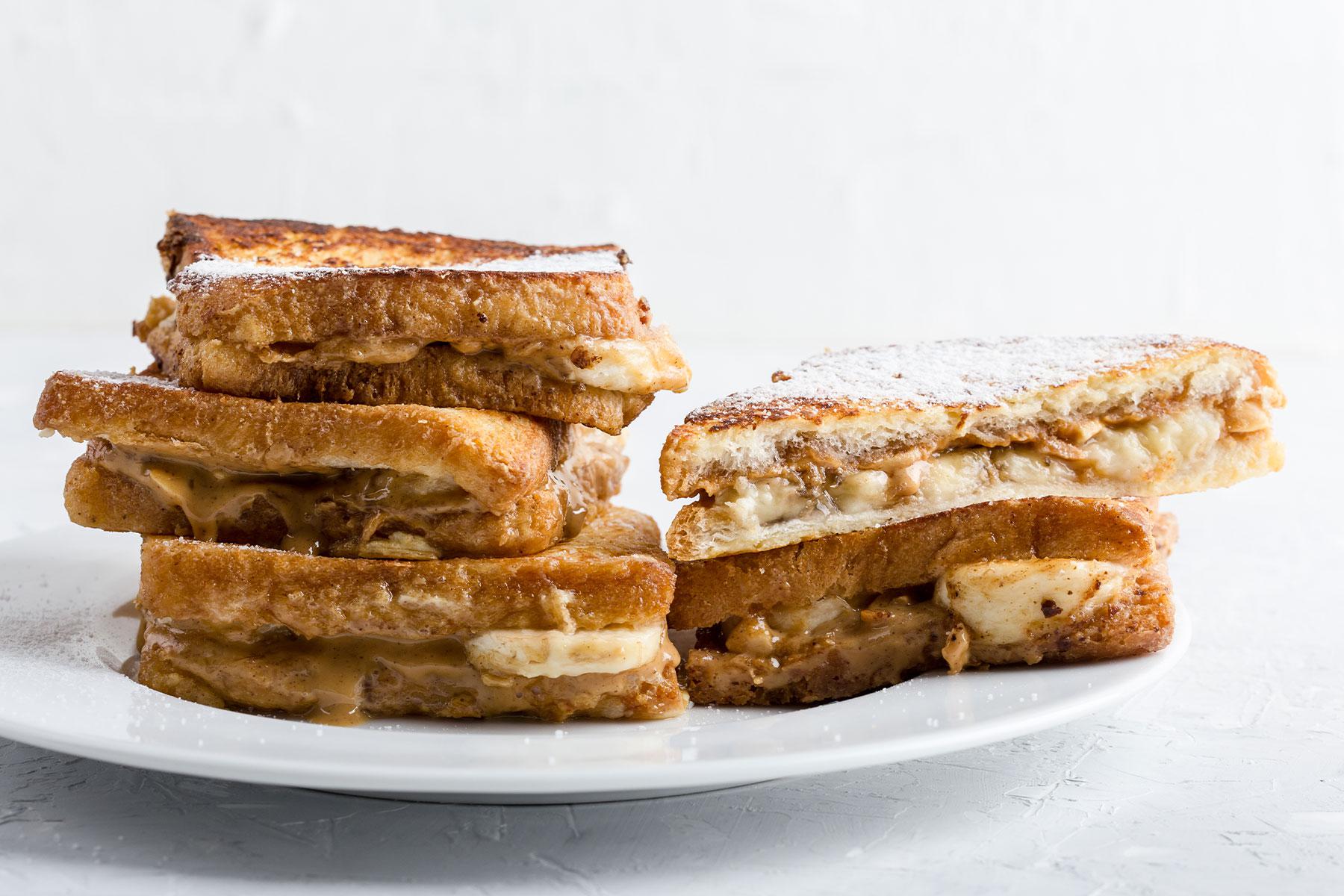 Grilled peanut butter banana sandwich on white plate.