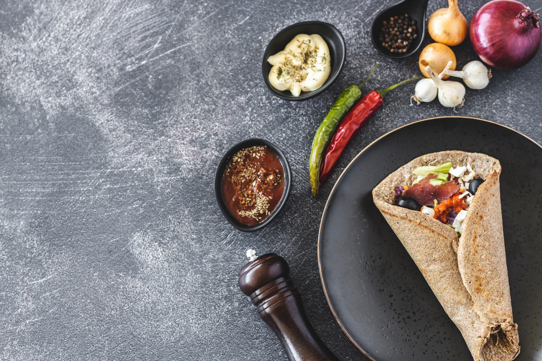 Overhead view of vegetable wrap on black plate.