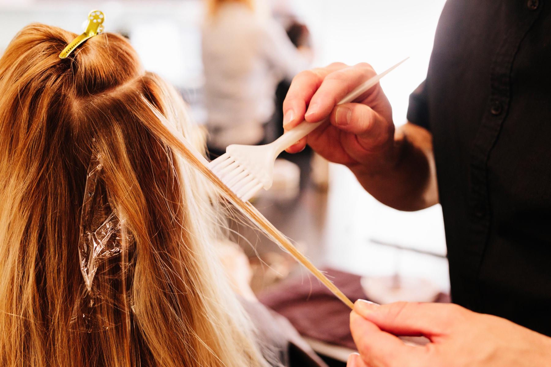 A red-headed woman getting her hair dyed at a salon.