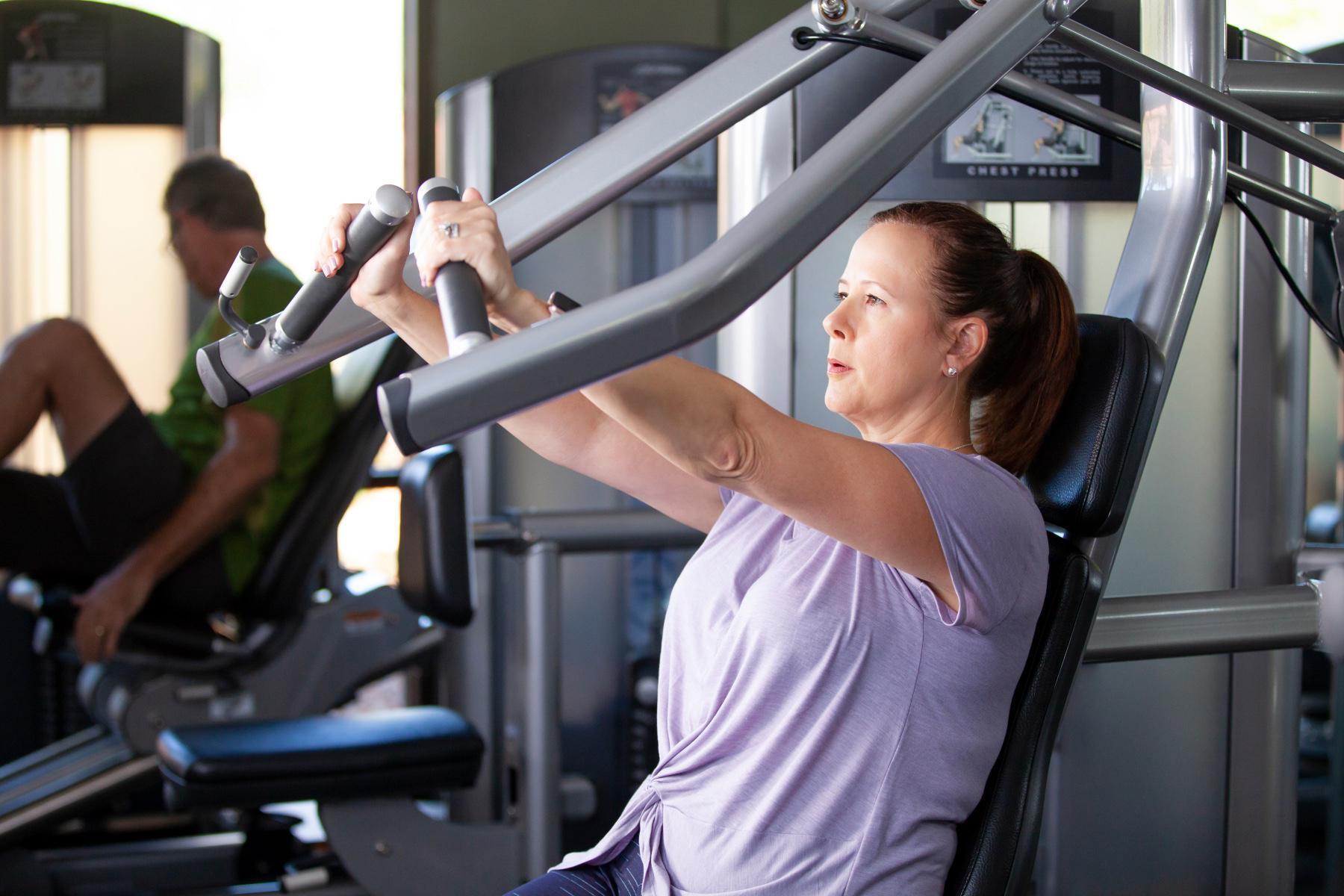 woman using chest press machine in gym