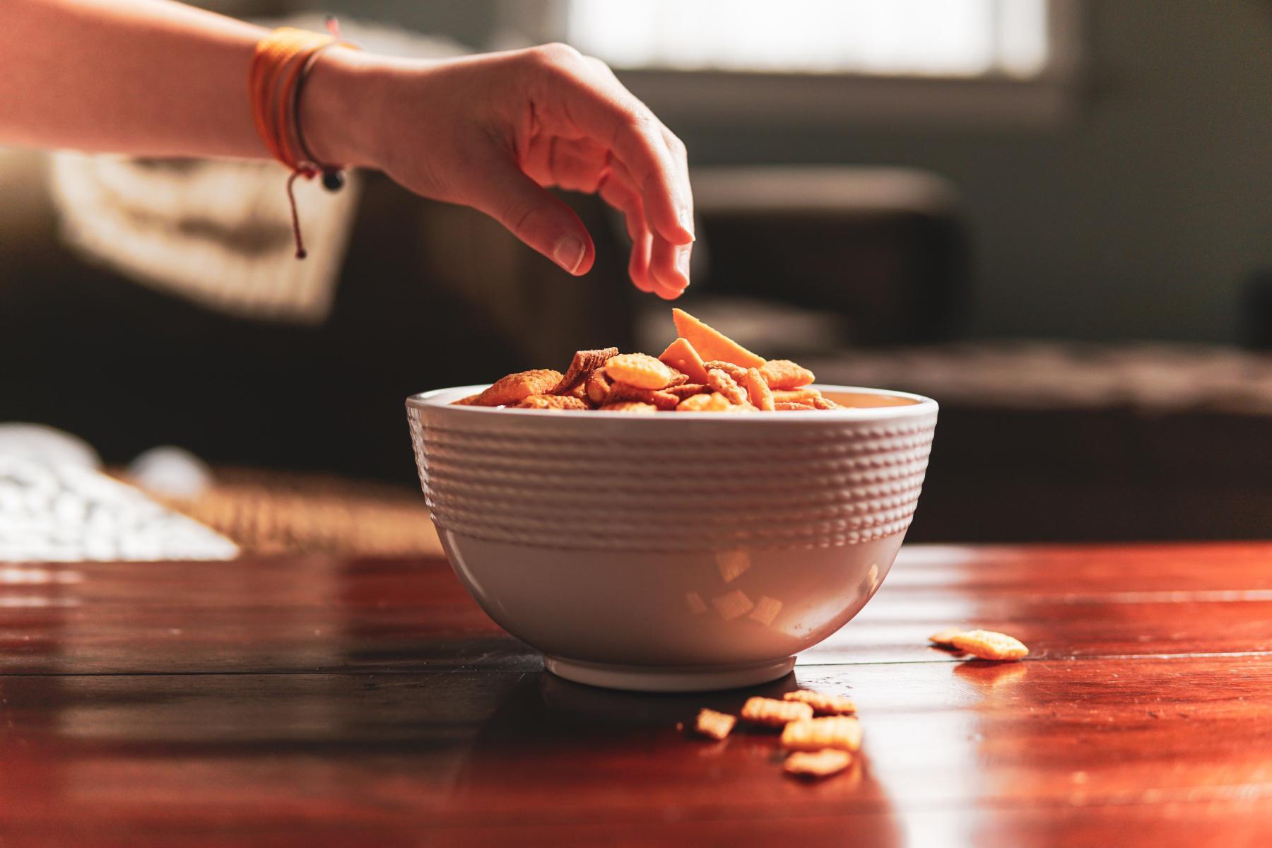 Hand reaching for bowl of snacks.