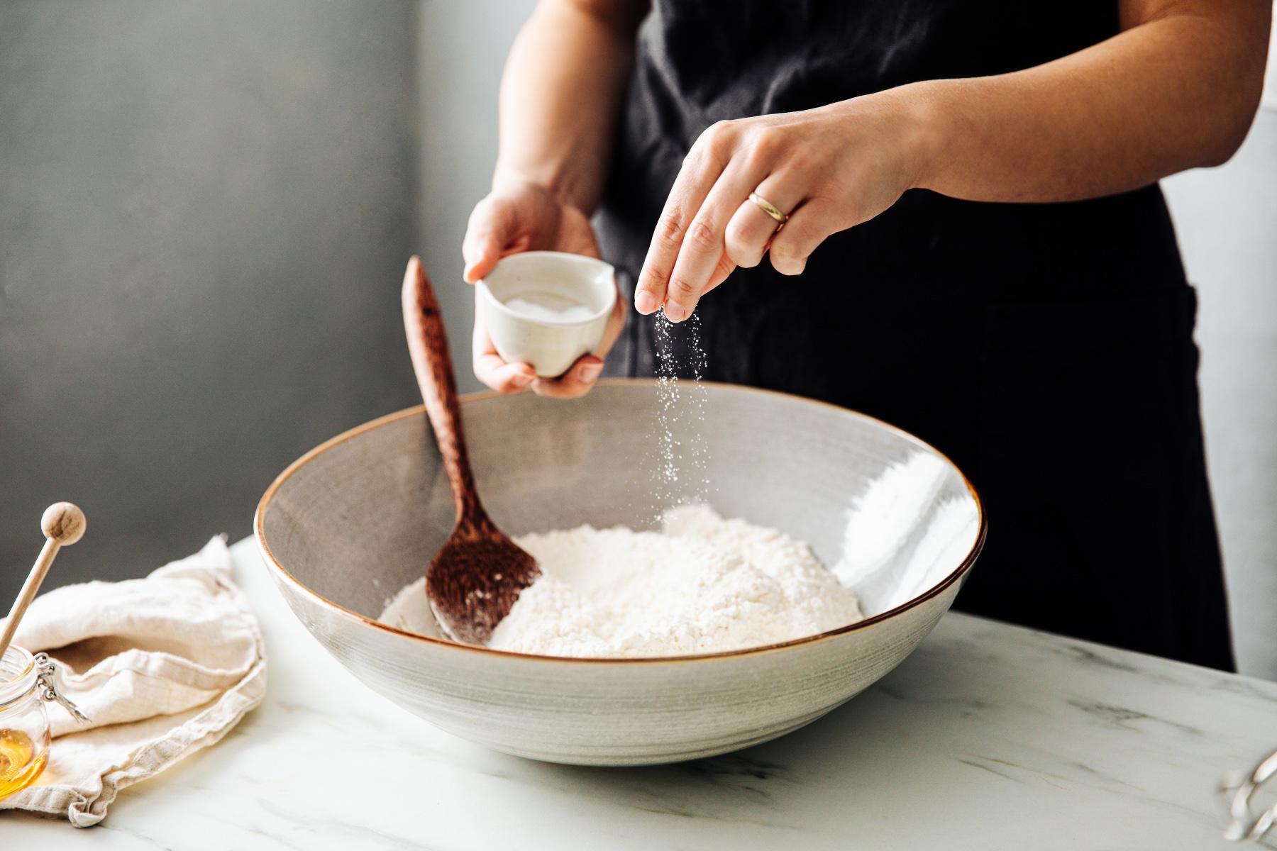 woman salting bowl of flour