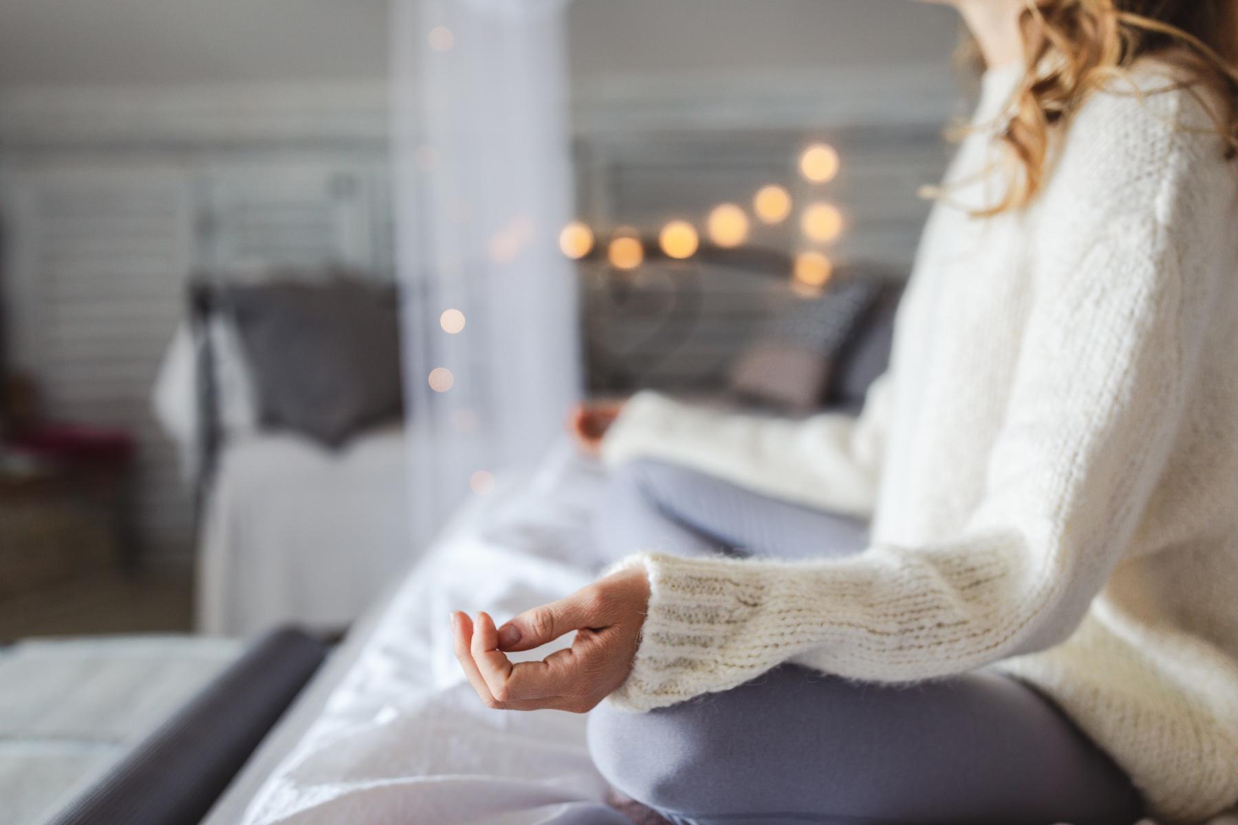 Woman meditating on her bed.