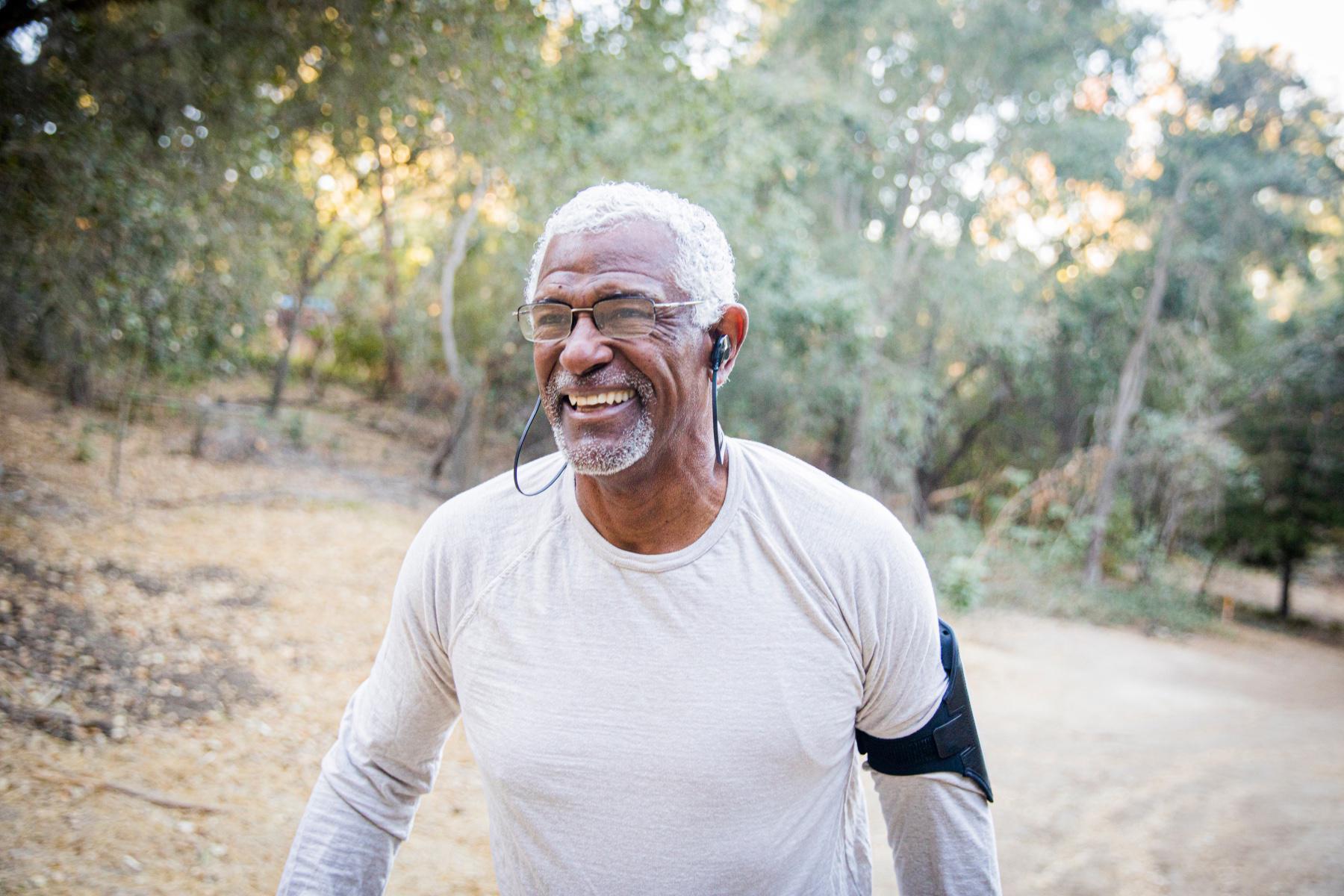 Man walking outside listening to music and smiling.