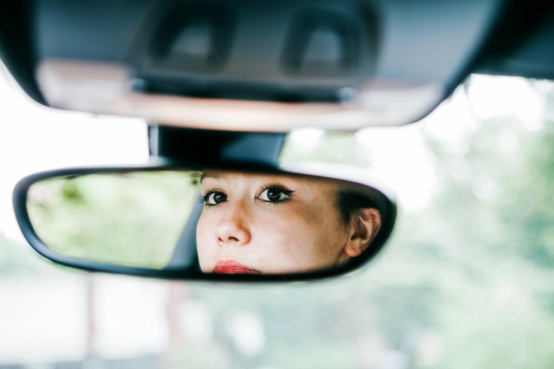 Woman looking in rear view mirror.