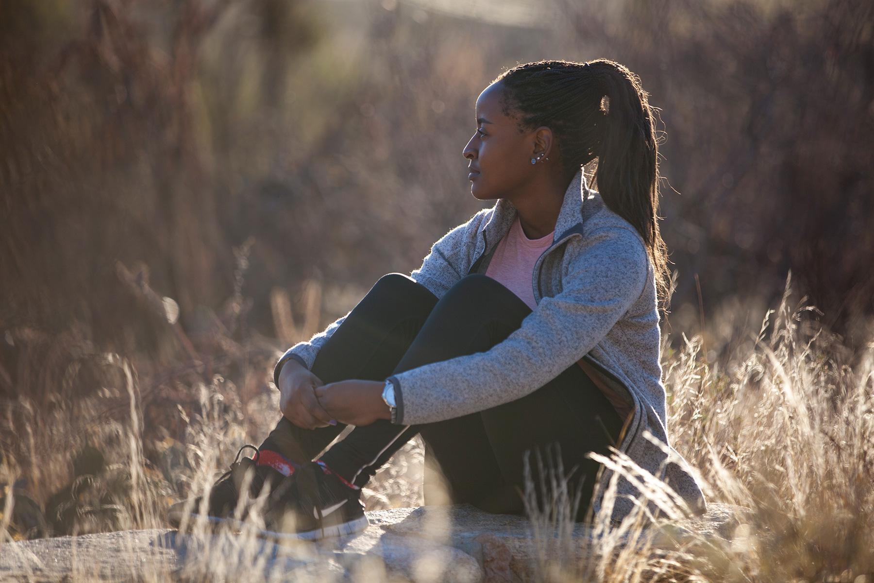 Woman sitting on rock outside looking out.