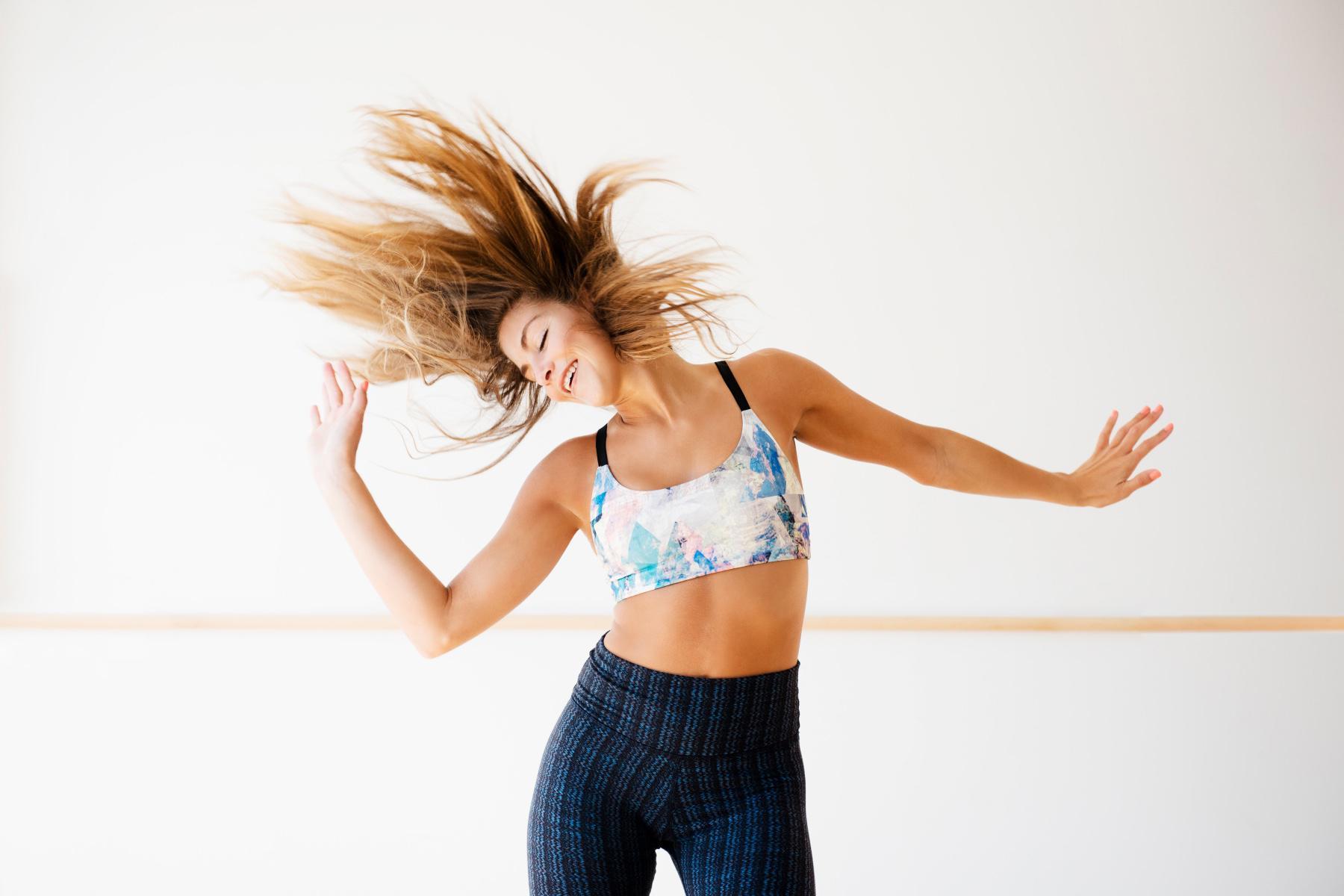 woman mid-dance move throwing hands to the side and flipping hair