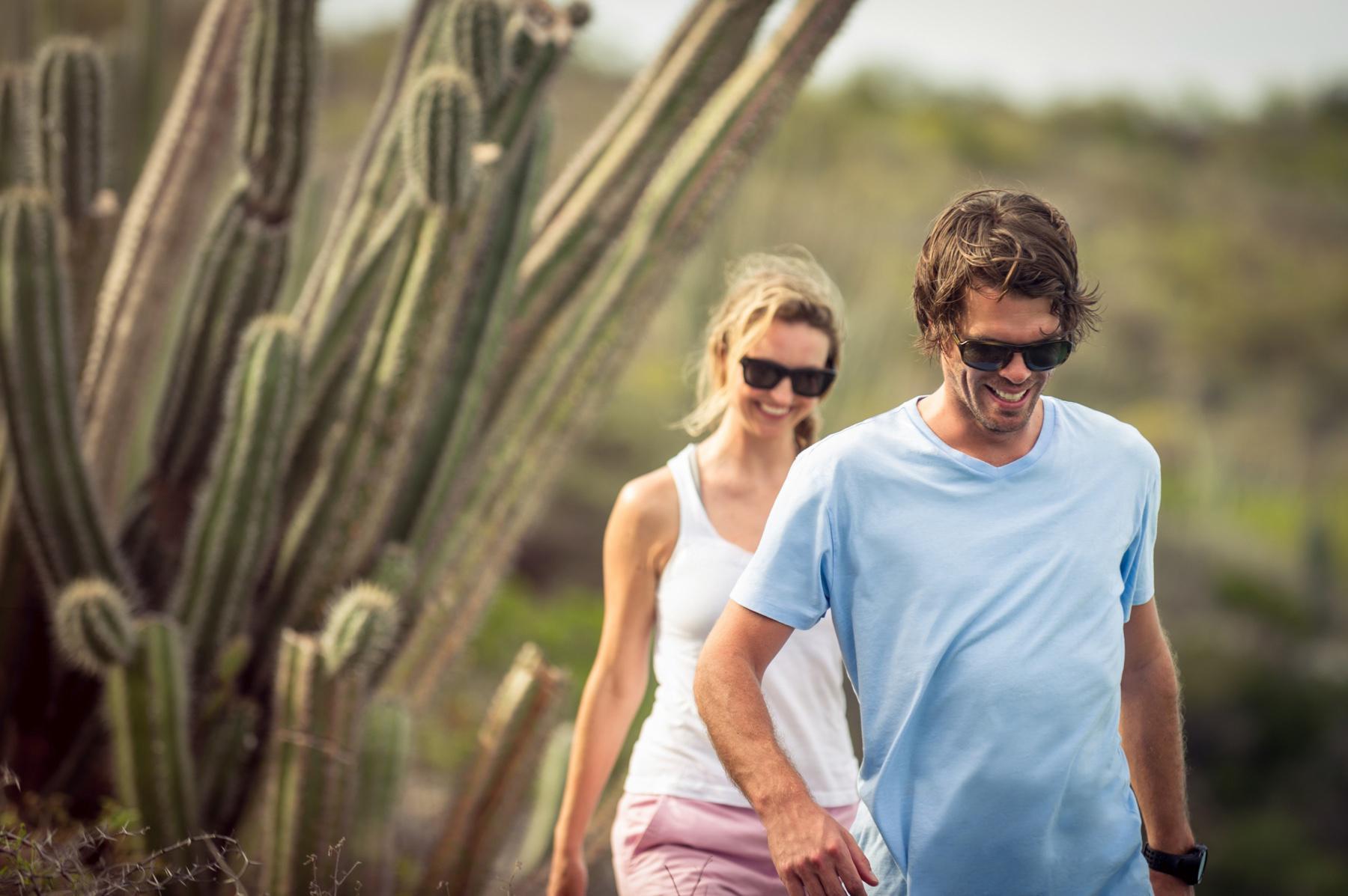 man and woman walking outside with cactus in background