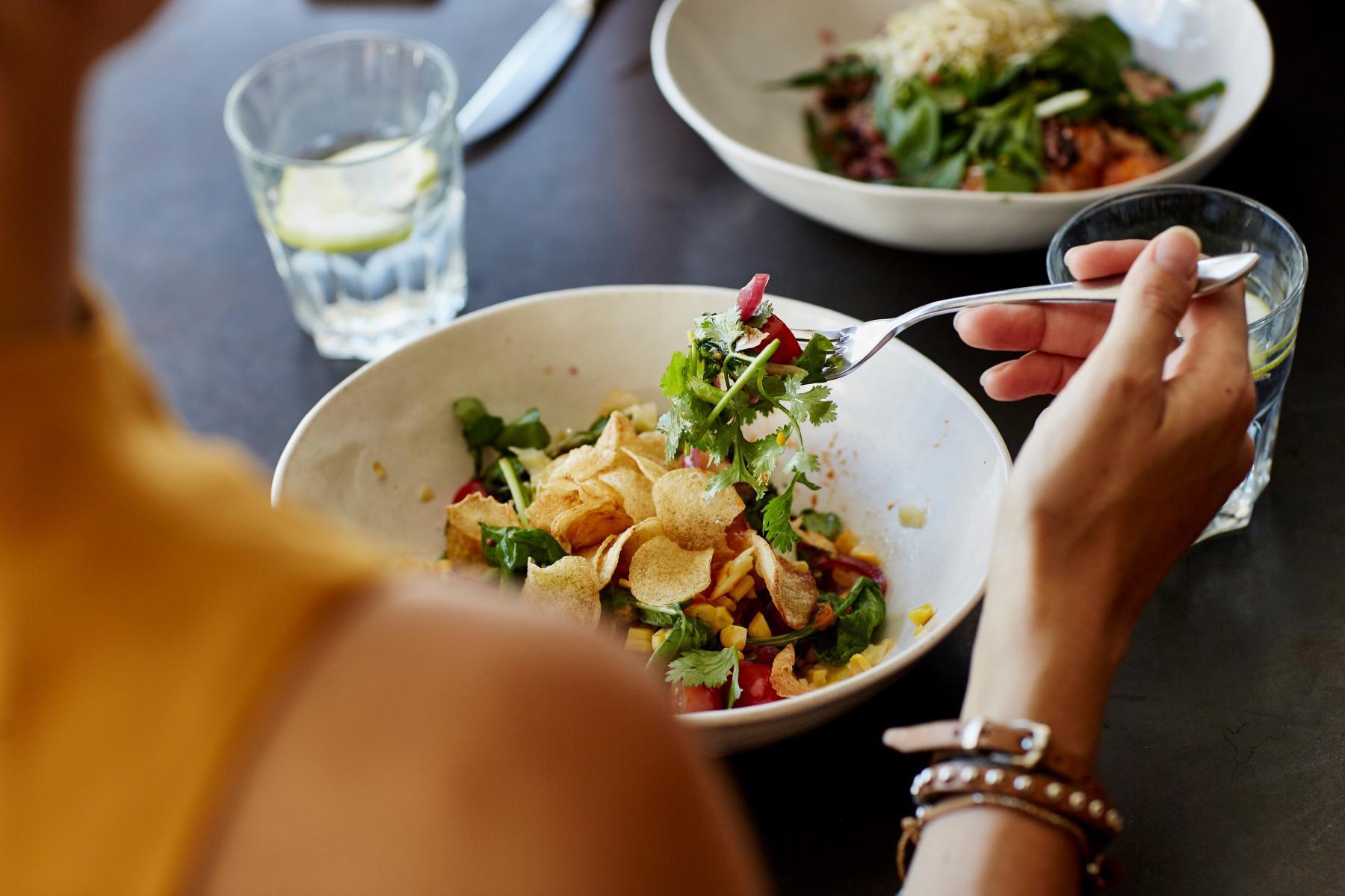 view from over a woman's shoulder of her eating a salad