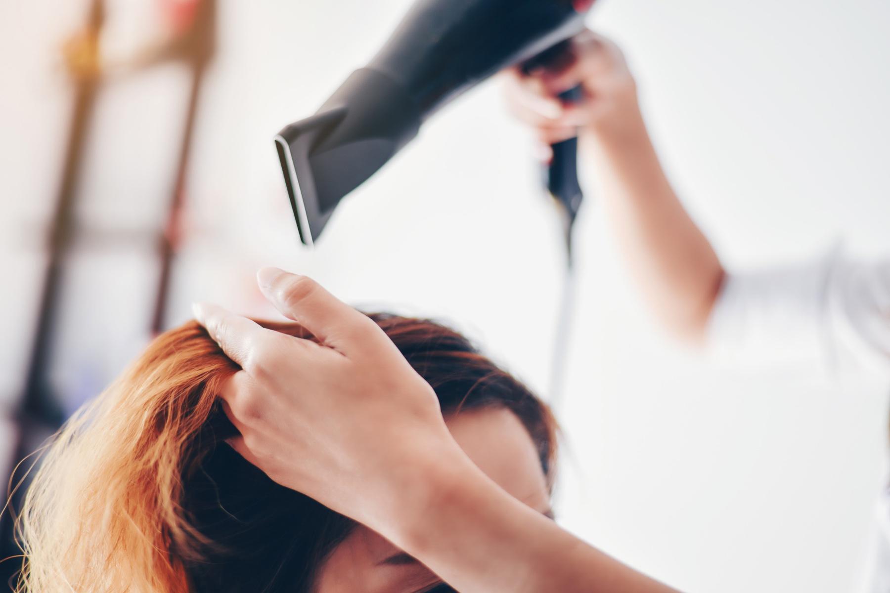 Woman getting her hair blow-dried at a salon.