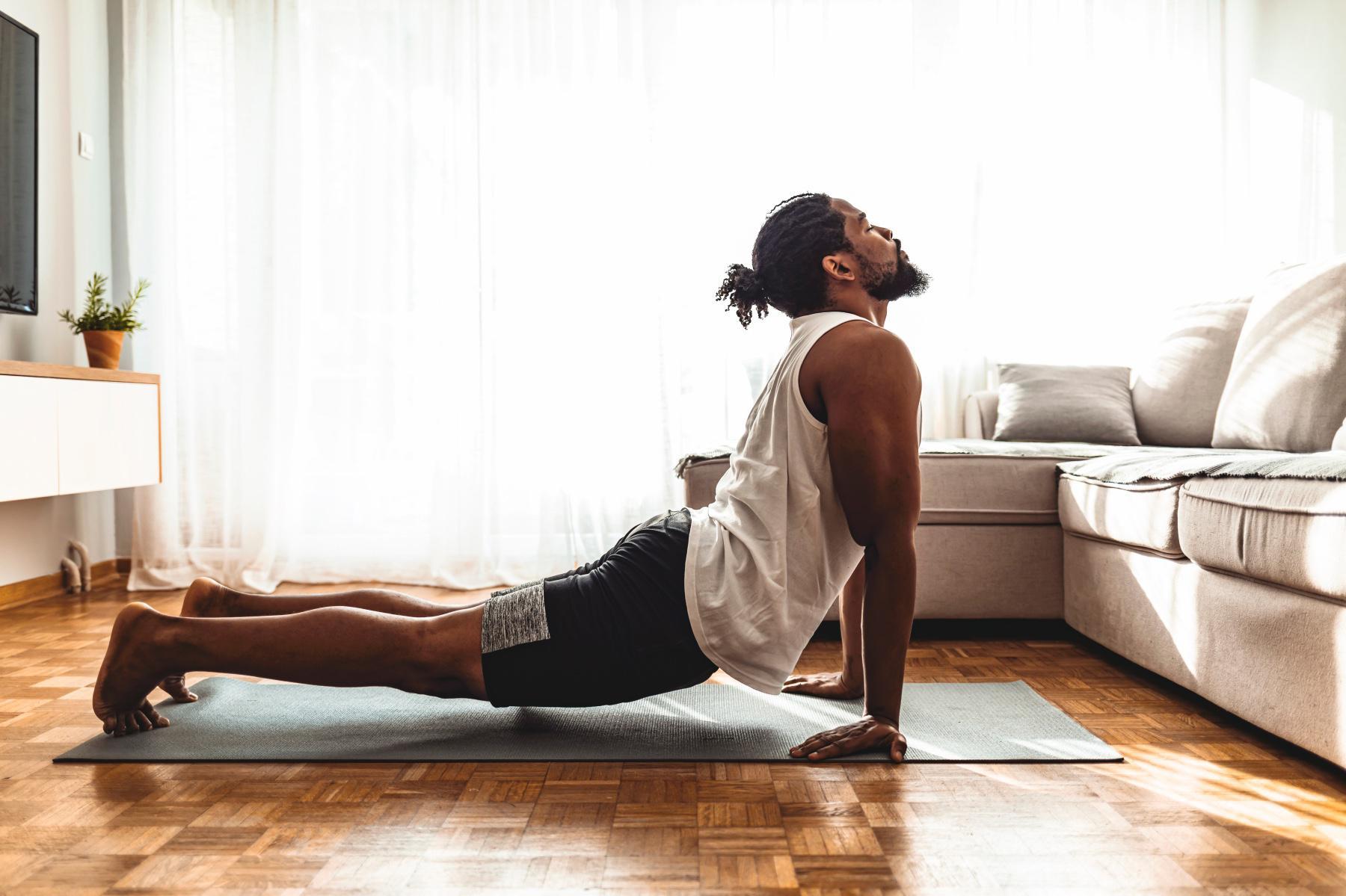 man from side at home on yoga mat in cobra yoga pose