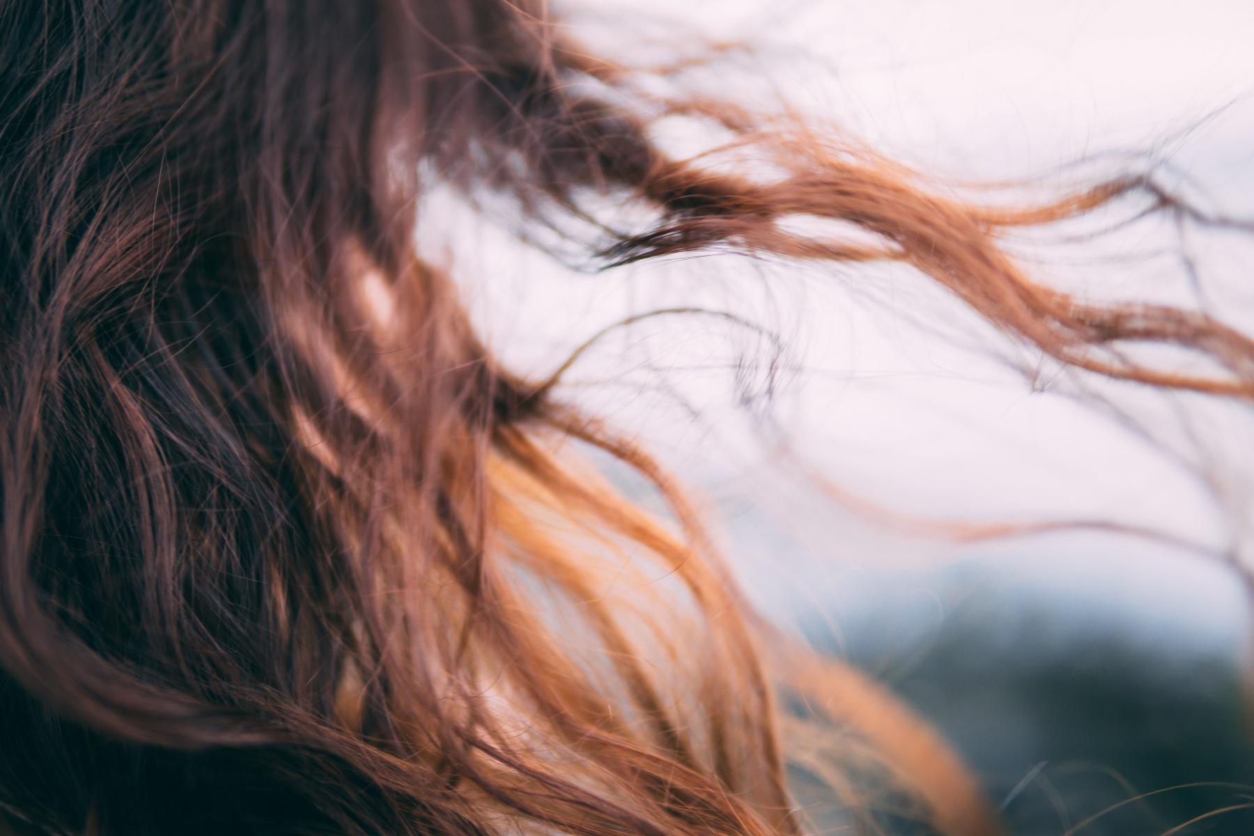 A close-up of a brunette woman's hair blowing in the wind.