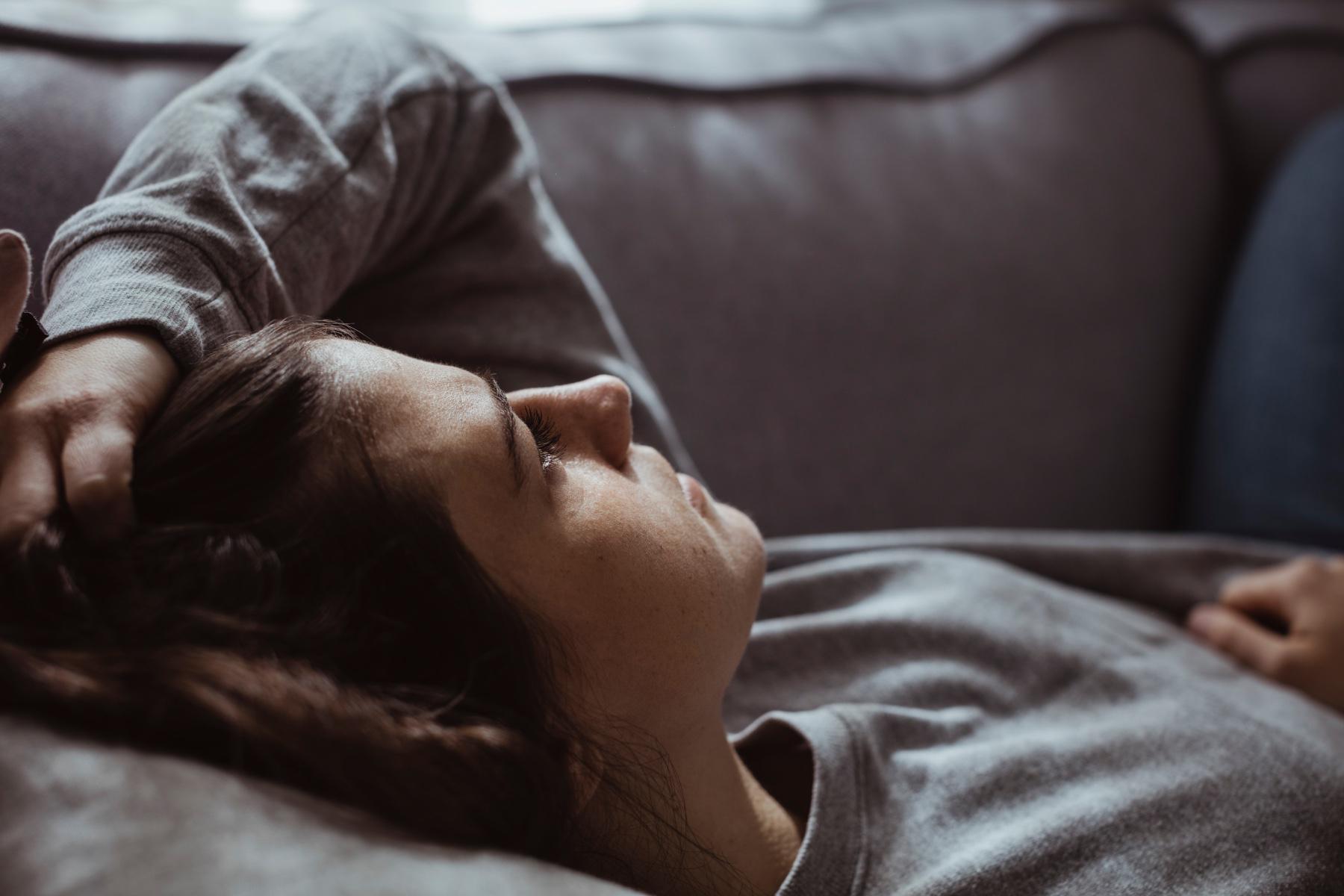 Close-up of stressed out woman laying on couch with her hand in her hair.