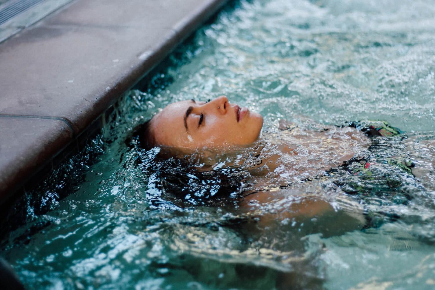 A woman smiling and splashing in the pool